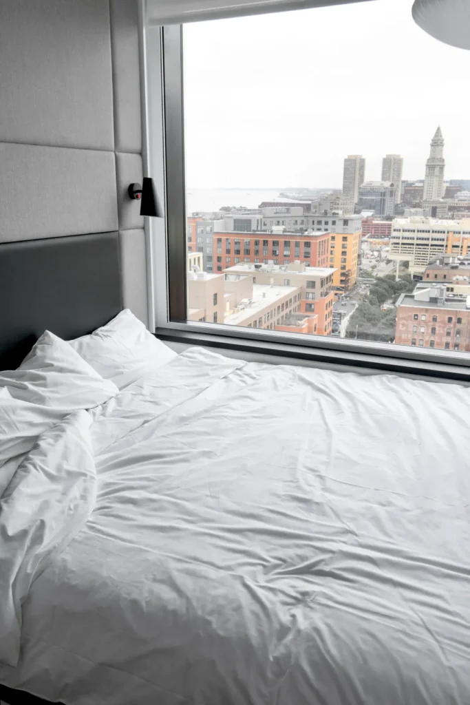 Cama ao lado de janela com vista para a cidade