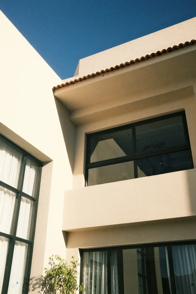 Fachada de casa com janelas de esquadria escura sob sol forte