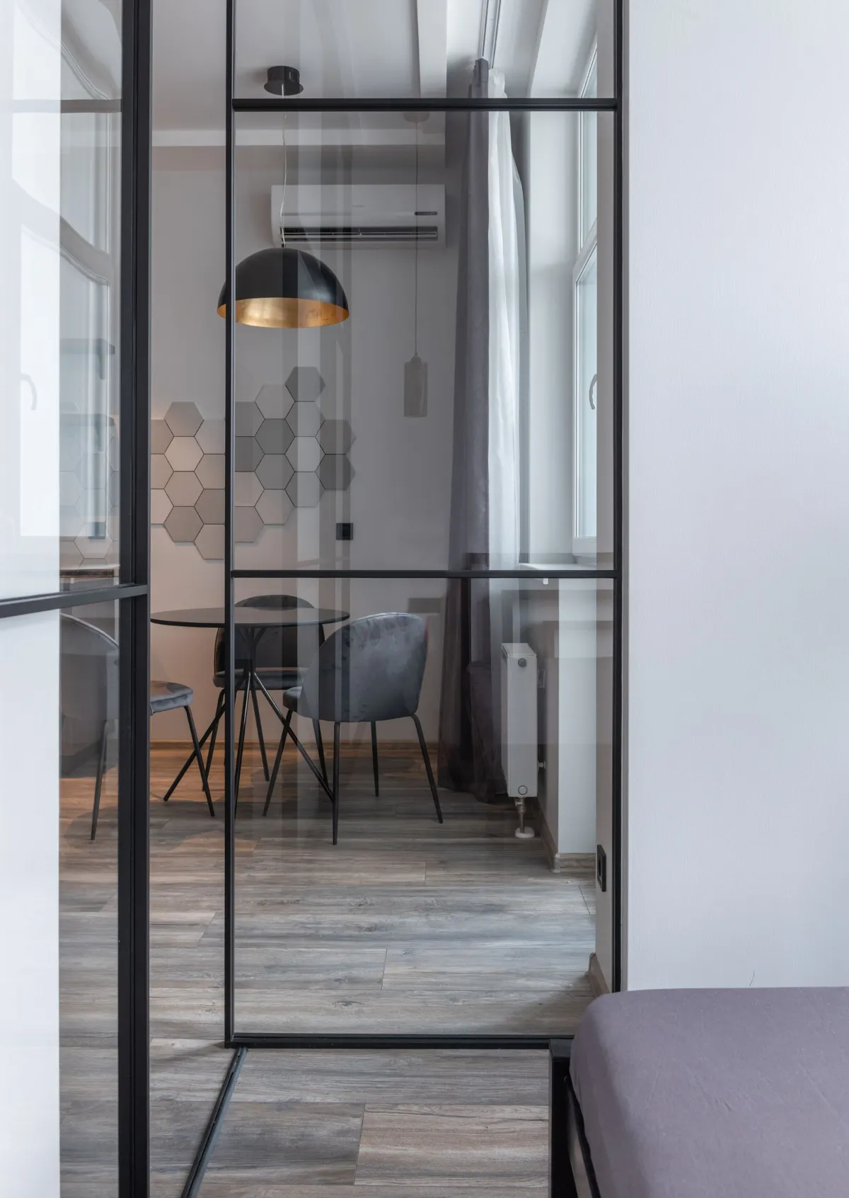Divisória de vidro com porta separando sala de jantar e dormitório em apartamento